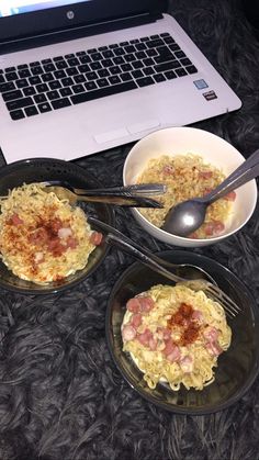 two bowls of food sit in front of a laptop