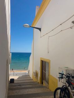 there is a bike parked on the side of this building next to the beach and ocean