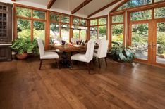 a dining room with wood flooring and large windows overlooking the trees in the distance