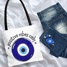 a bag with an evil eye on it sitting next to some denim shorts and a pair of jeans