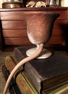 an odd looking vase sitting on top of two books with a hose coming out of it