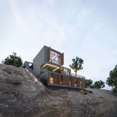 a house on top of a cliff with trees in the background