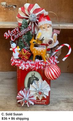 an old tin can is decorated with christmas decorations and santa's helper ornament