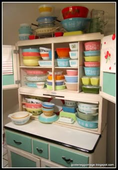 a cabinet filled with lots of colorful bowls and pans on top of it's shelves