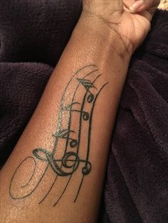 a person with a tattoo on their arm that has musical notes and trebles