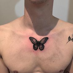 a man's chest with a butterfly tattoo on his chest and two small flowers