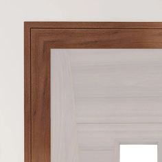 a mirror that is on the wall in front of a white wall and wooden frame