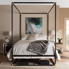 a four poster bed in a bedroom with hardwood flooring and beige walls, along with a painting on the wall