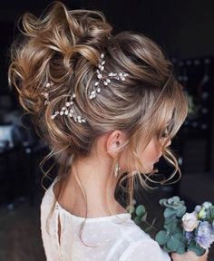 a woman with her hair in a messy updo and some flowers on the side