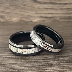 two wedding rings with white and black wood inlays on top of each other