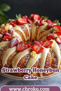 a strawberry honey bundt cake with icing and strawberries on top, sitting on a plate