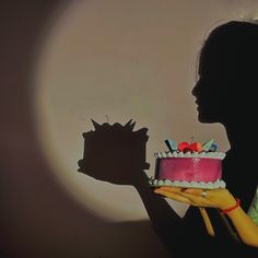 a woman holding a cake in front of her face with the shadow of a cat on it