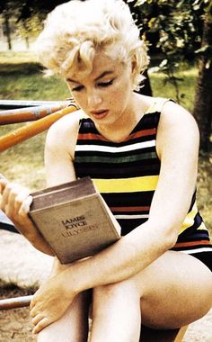 a woman sitting on the ground with a book and baseball bat in her hand,