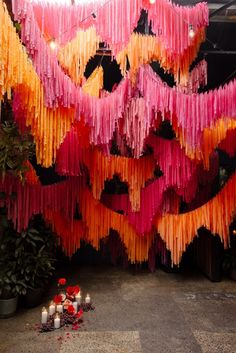 colorful streamers are hanging from the ceiling in front of candles and potted plants