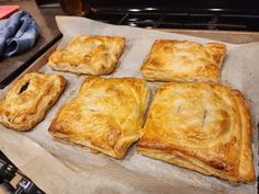 four square pastries sitting on top of a piece of parchment paper in front of an oven