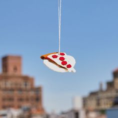 a slice of pizza hanging from a string in front of a cityscape background