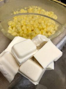 cubes of ice cream sit next to corn in a bowl