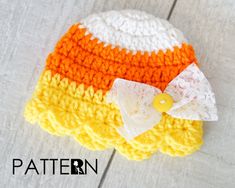 an orange, yellow and white crochet hat with a bow on it's side