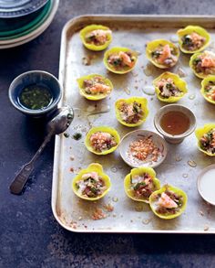 small cups filled with food sitting on top of a metal baking tray next to sauce