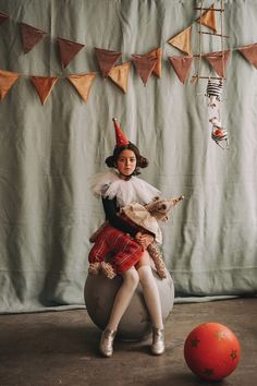 a woman sitting on top of a ball holding a dog