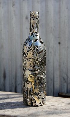 a bottle that is sitting on top of a wooden table next to a fence with lots of keys in it