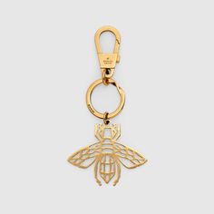 a gold keychain with a bee on the front and bottom, hanging from it's side