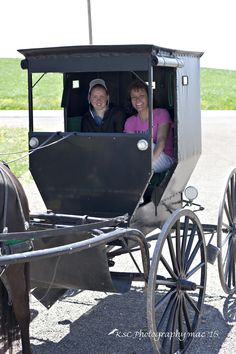 two people are riding in a horse drawn carriage