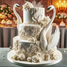 a three tiered cake with swans on top and flowers around the edges, sitting on a table