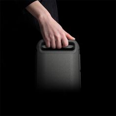 a person holding onto a black suitcase with their hand on the handle and it's lid