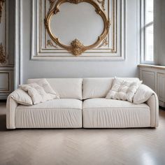 a white couch sitting in front of a painting on the wall next to a window