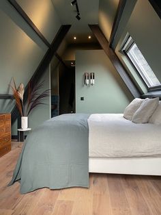 a bed sitting in the middle of a bedroom next to a dresser and window on top of a wooden floor