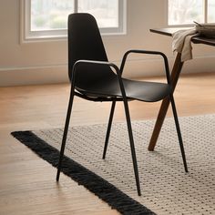 two black chairs sitting on top of a wooden floor next to a table and window