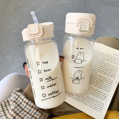 a person holding two baby bottles next to each other