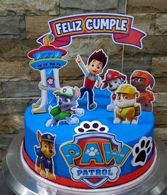 a blue cake with paw patrol characters on it's top and the words feliz cumple