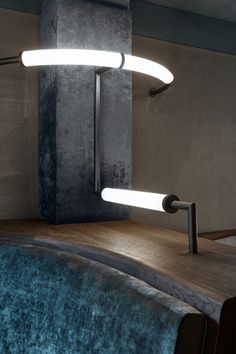 two lights that are on top of a wooden table in front of a wall with concrete walls