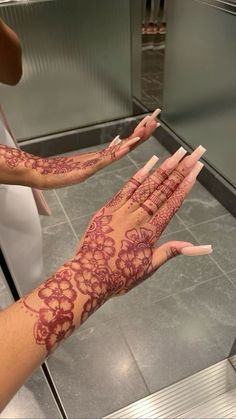 two hands with hendikes painted on them in front of a mirror and tiled floor