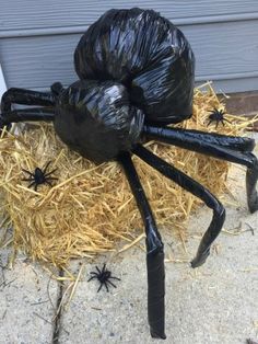 a large black spider sitting on top of hay next to a building with it's legs wrapped in plastic