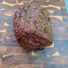 a piece of meat sitting on top of a cutting board covered in spices and seasoning