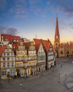 an aerial view of old buildings with a clock tower in the background at sunset or dawn