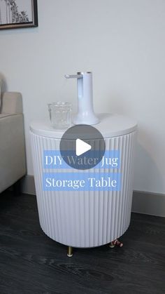 the diy water jug storage table is on display in a living room with black wood flooring