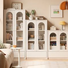 a living room filled with white furniture and lots of bookshelves on top of it