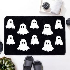 a pair of slippers sitting on top of a black rug with white ghost faces