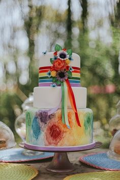 a multi - colored cake on a table with plates and napkins