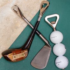 three golf balls, two clubs and one putter on a green surface with marble flooring