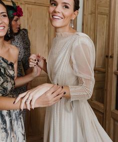 two women standing next to each other in front of wooden closets holding onto one another's hands