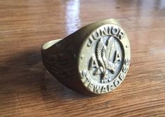 a ring with an eagle on it sitting on a wooden table in front of a window