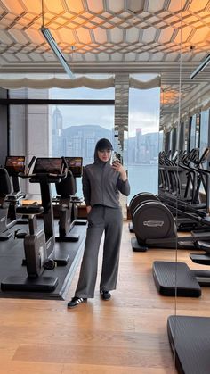 a woman taking a selfie in front of an exercise room with treadmills