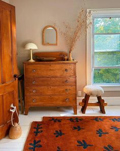 a bedroom with a dresser, mirror and rug