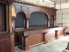 a large wooden bench in a room with black walls and wood paneling on the wall