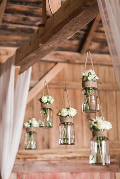 hanging mason jars filled with white flowers and greenery are the focal point for this rustic wedding